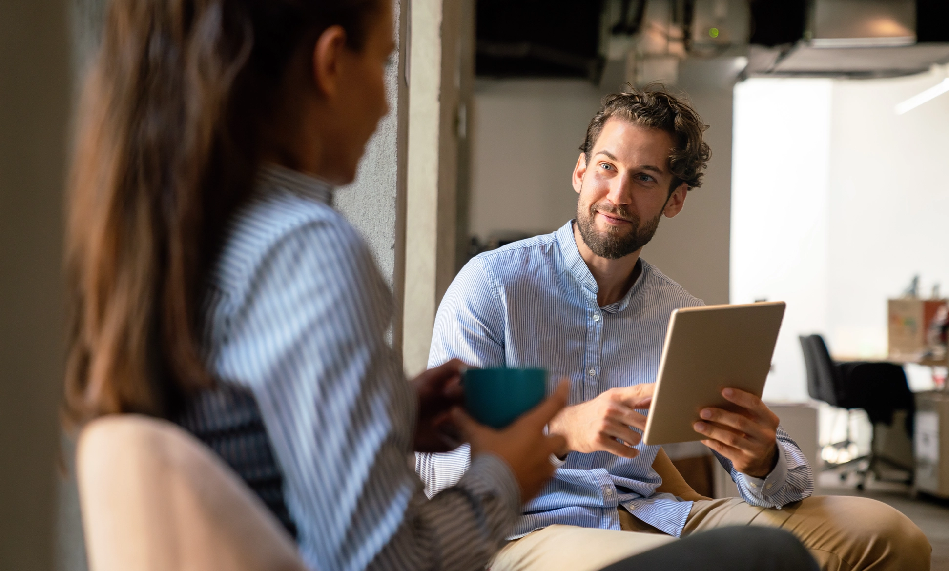 A man talking with a female colleague in his office.