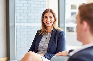 Businesswoman smiling during a conversation with a colleague in a modern office setting.