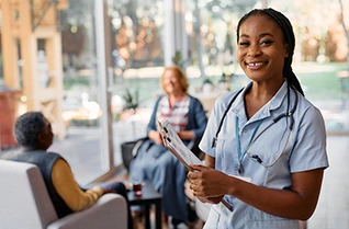 Smiling nurse holding a clipboard in a clinic waiting area, with patients seated in the background.